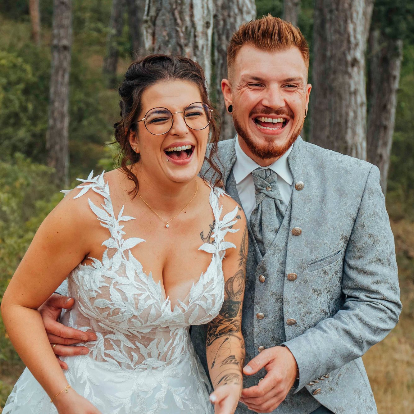 Hochzeitsfotos Main Spessart Ein glückliches Brautpaar im Freien, beide lachen und tragen festliche Kleidung.