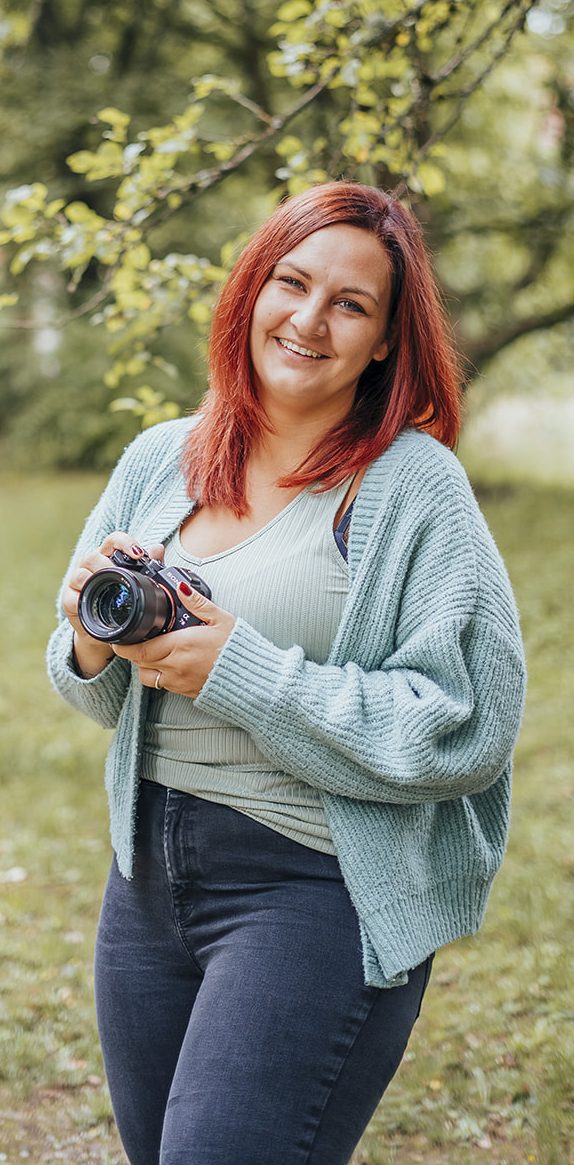 Fotograf Marktheidenfeld Lächelnde Frau mit roten Haaren in einem farbenfrohen Spielplatz-Gerüst.
