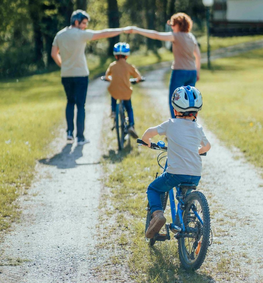 Familienfotografin in Main Spessart Familie mit zwei Kindern auf Fahrrädern, die auf einem Weg in der Natur unterwegs sind.