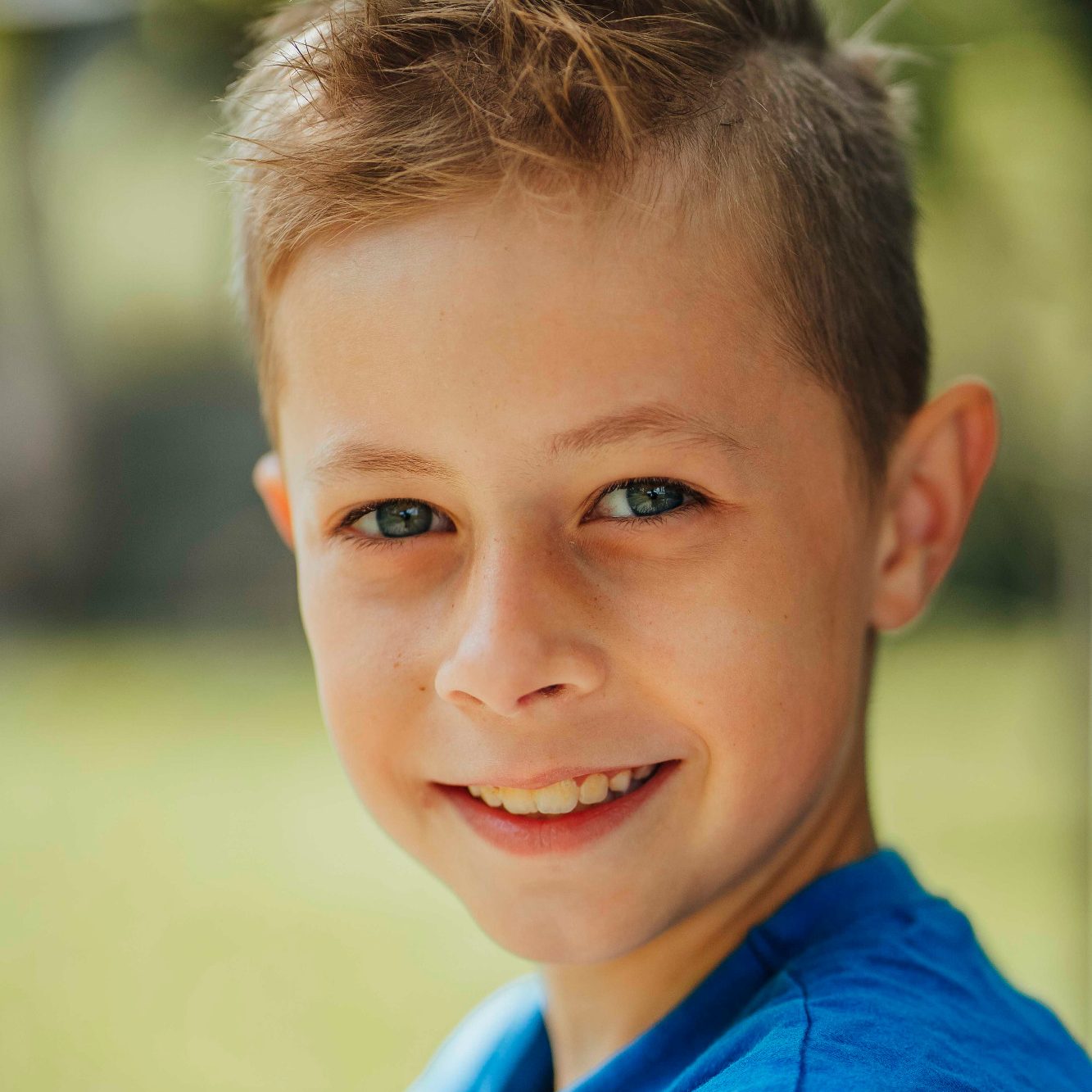 Grundschul Bilder in Main Spessart Lächelnder Junge mit kurzen, blonden Haaren und blauen Augen, trägt ein blaues Shirt.