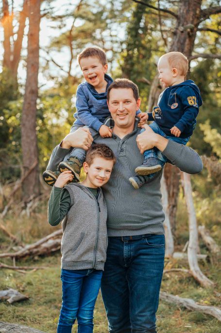 Fotograf Main Spessart und Umgebung Ein Mann mit drei fröhlichen Kindern im Wald, zwei Kinder auf seinen Armen.